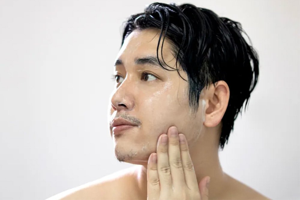 Seorang pria sedang mencoba sabun cuci muka pria untuk kulit sensitif dan berjerawat